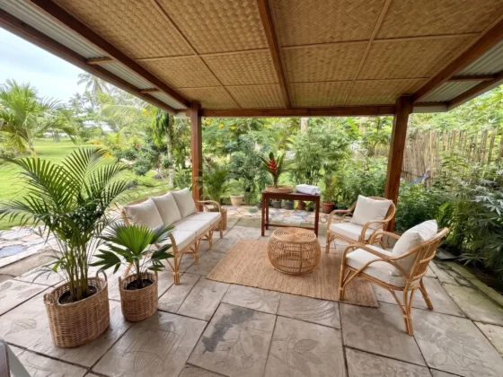 The arrival lounge, rattan seating on stone pavers under a bamboo ceiling