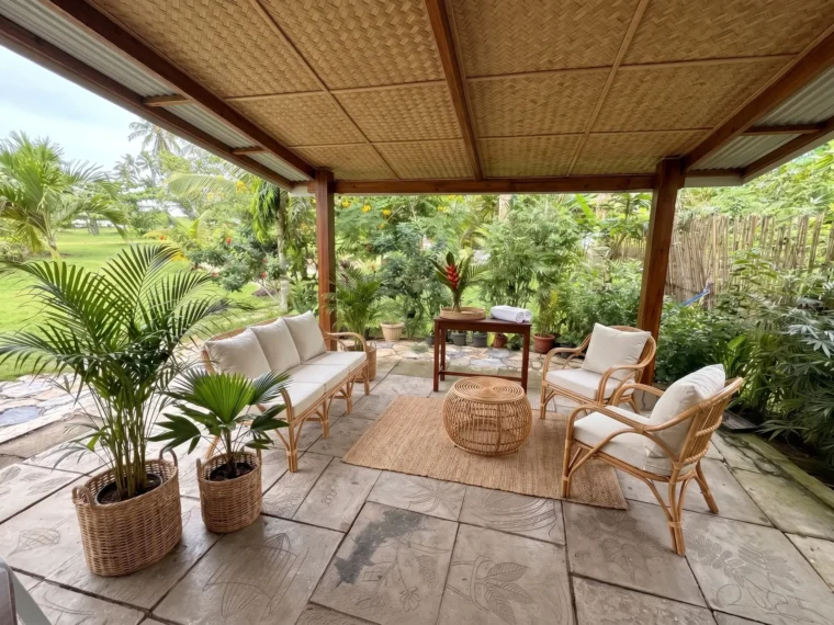 The arrival lounge, rattan seating on stone pavers under a bamboo ceiling