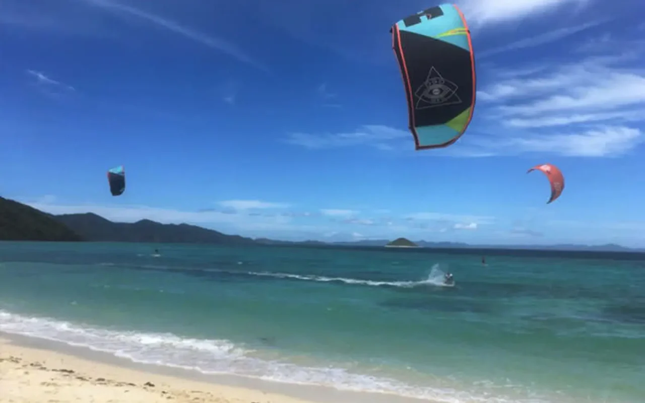 The beach at Eastwind with kites in the air over turquoise water