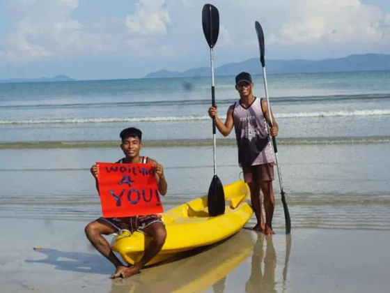 Two staff members with a yellow kayak on the beach