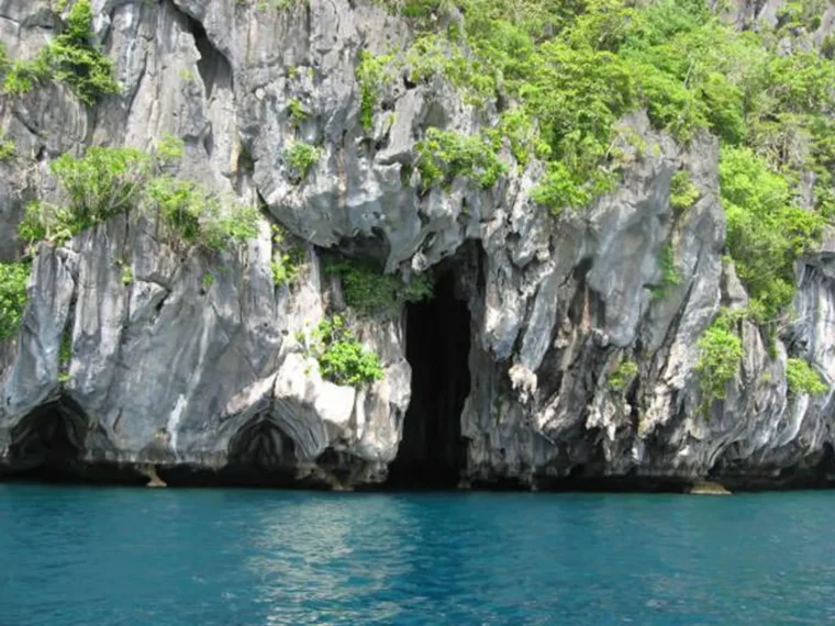 A limestone cliff and cave entrance on a Bacuit Bay island tour