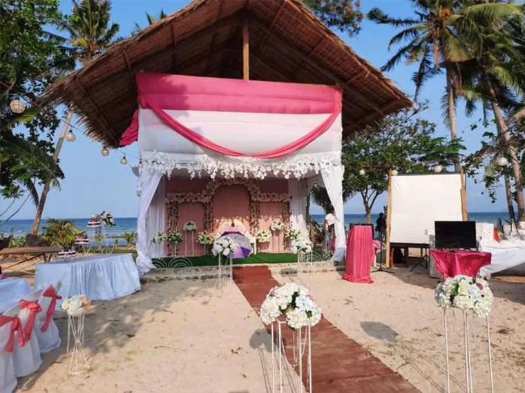 A pavilion decorated with pink and white drapes set up for an event