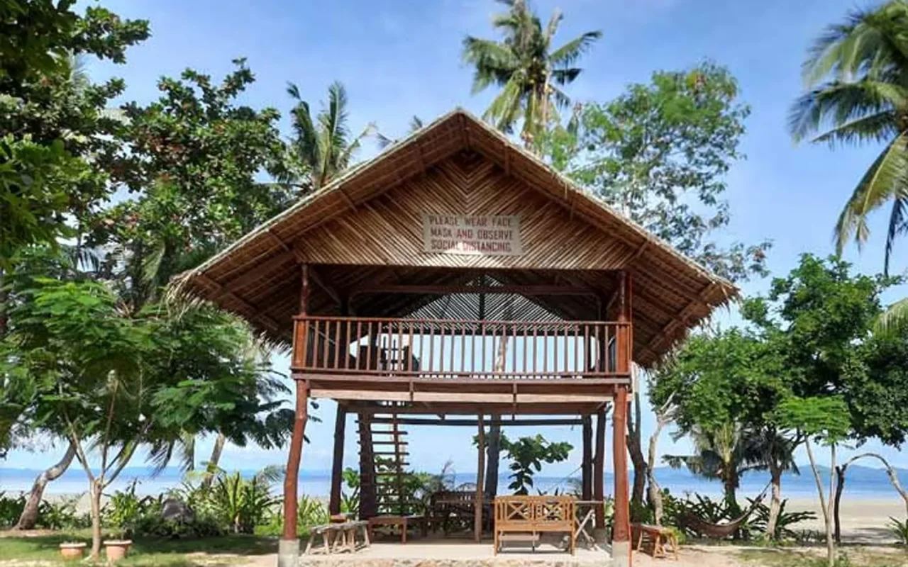 The nipa-roofed spa hut on the lawn under coconut palms