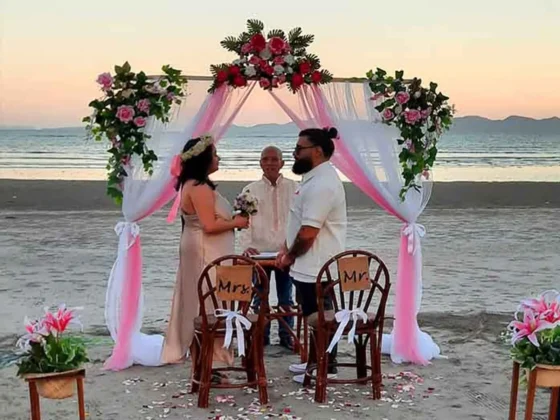 A beach wedding ceremony under a floral arch