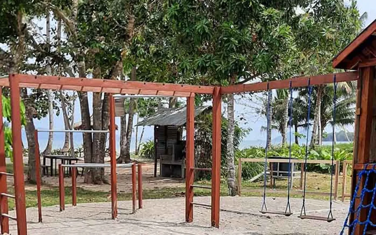 The open-sided function structure with timber posts beside the lawn and shoreline
