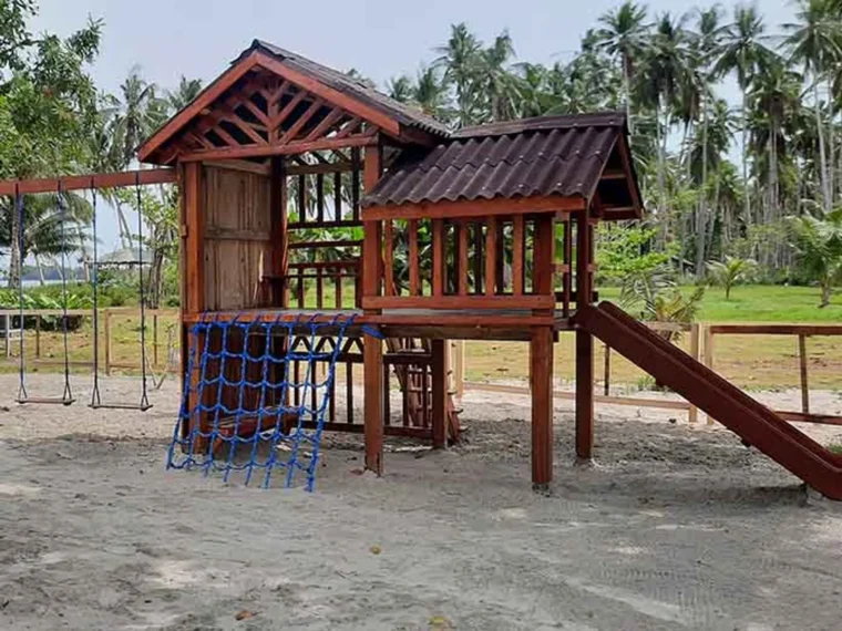 A wooden playground fort with slide and climbing net