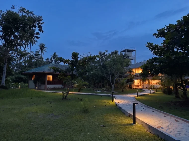 The sand path lit low, running toward the water at night