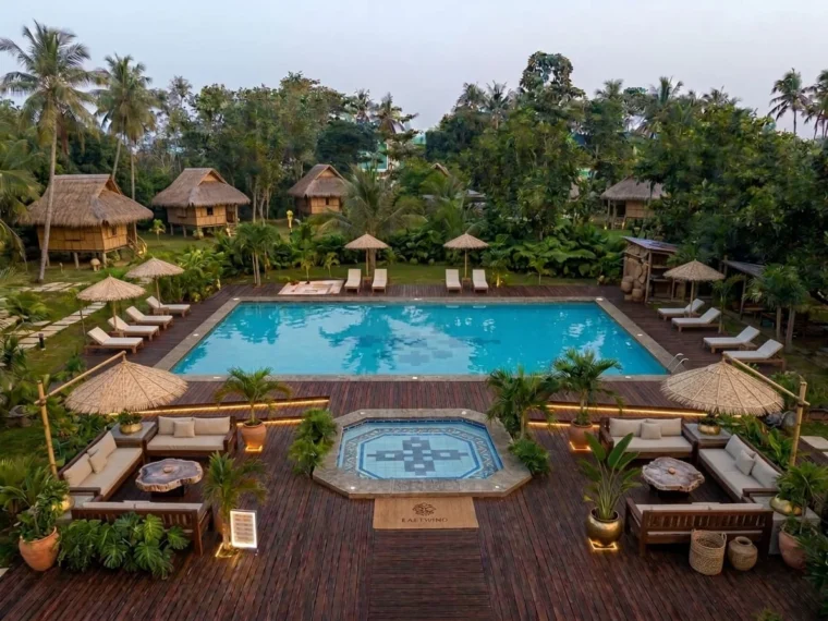 Aerial of the pool deck at dusk with nipa villas beyond